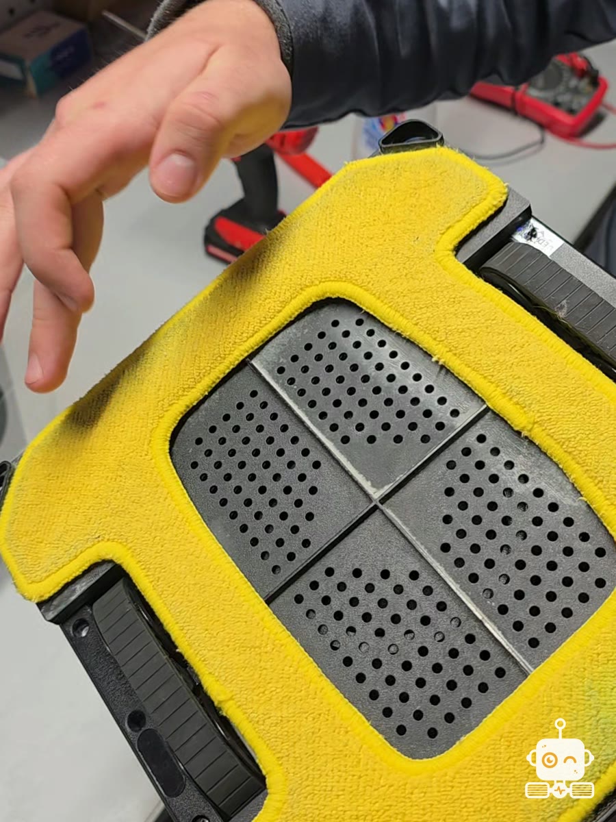 Un robot de spălat geamuri cu laveta galbenă, pe bancul de lucru