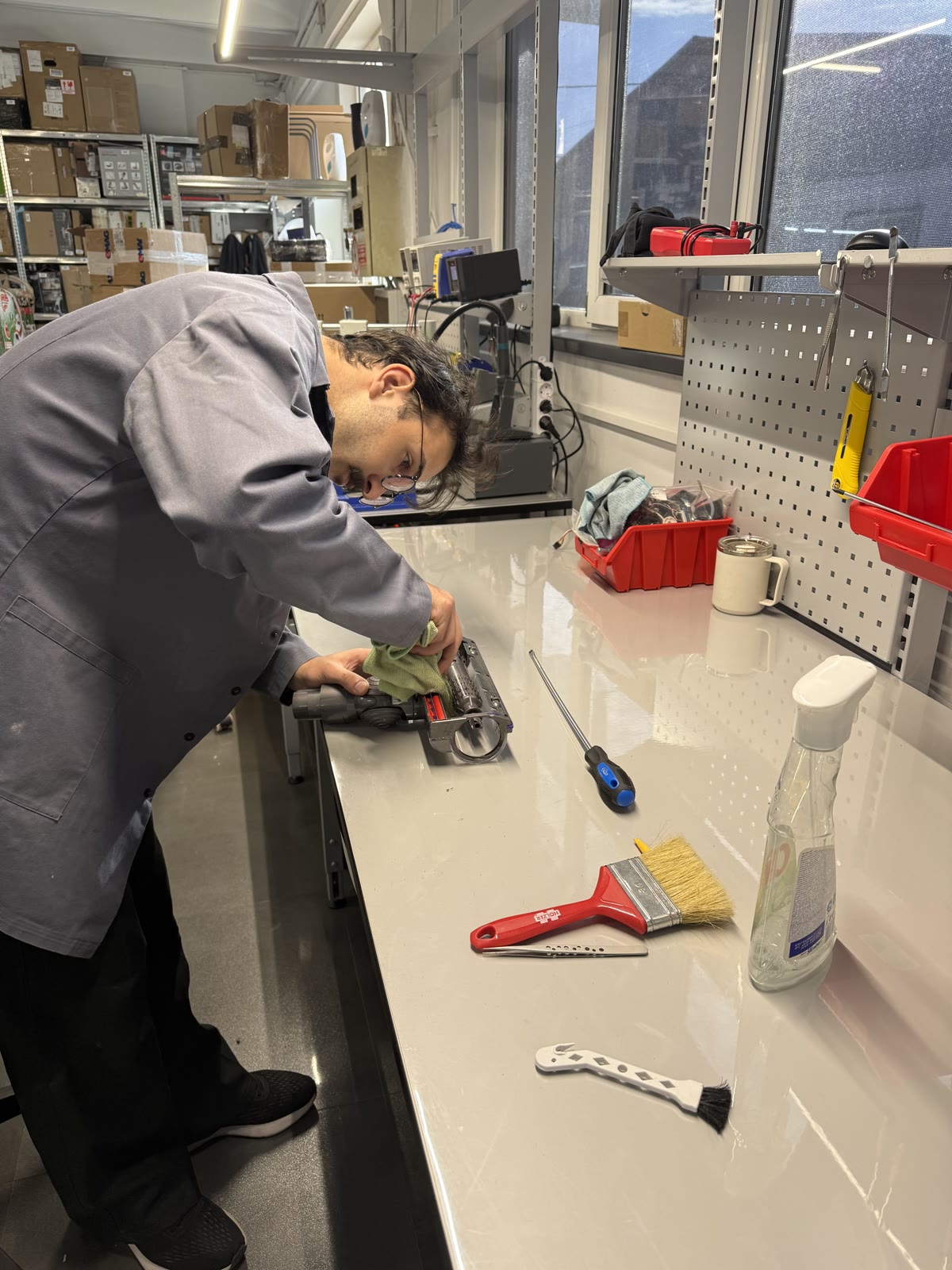 Un coleg curăță peria unui aspirator vertical Dyson pe bancul de lucru al Clinicii Roboților