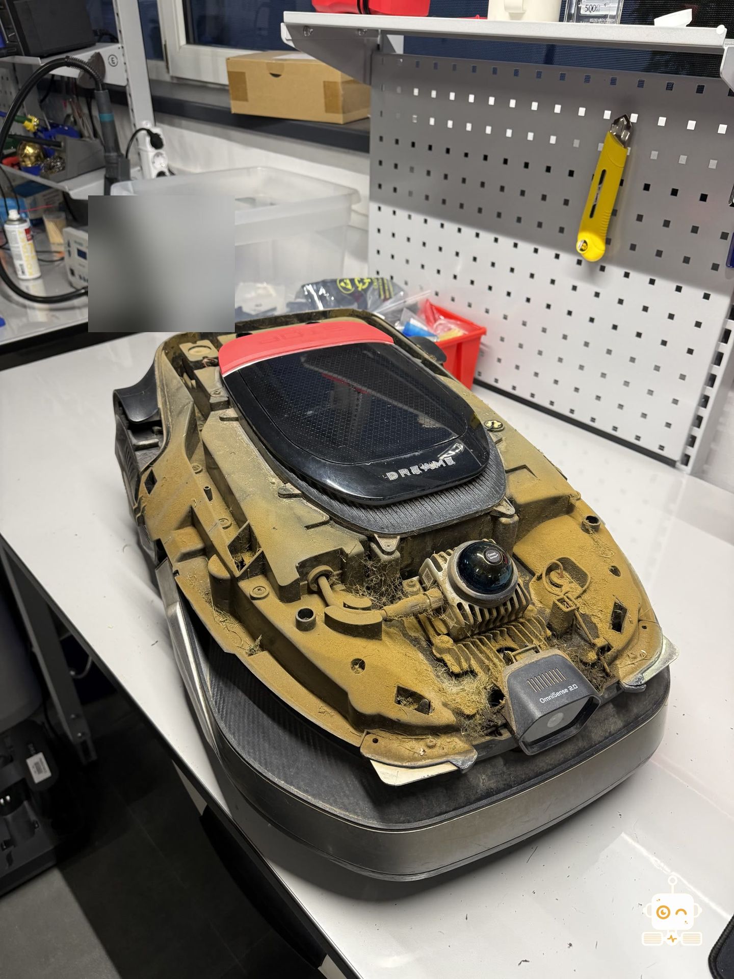 Un robot de gazon Dreame plin de praf, pe bancul de lucru