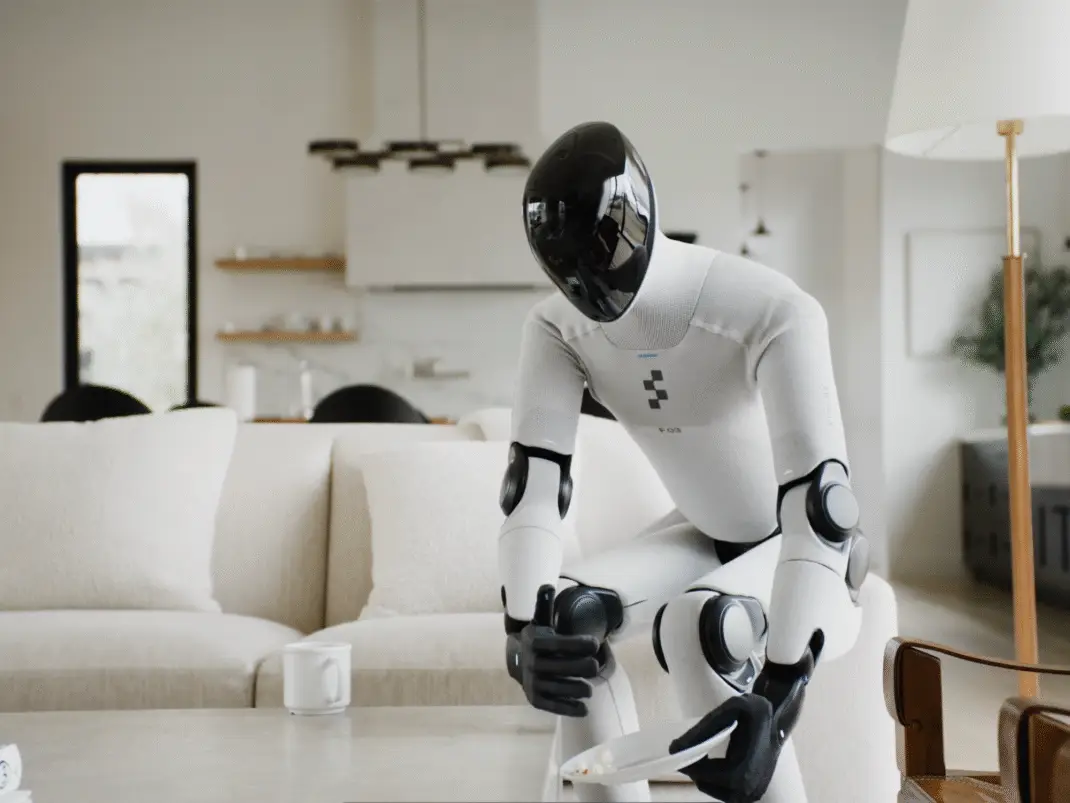 Robotul humanoid Figure 03 stând pe canapea ținând o farfurie în mâini într-un living modern